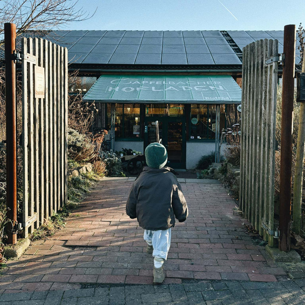 KI generiert: Ein Kind läuft auf einen Laden zu. Text auf dem Schild: "Hofladen".