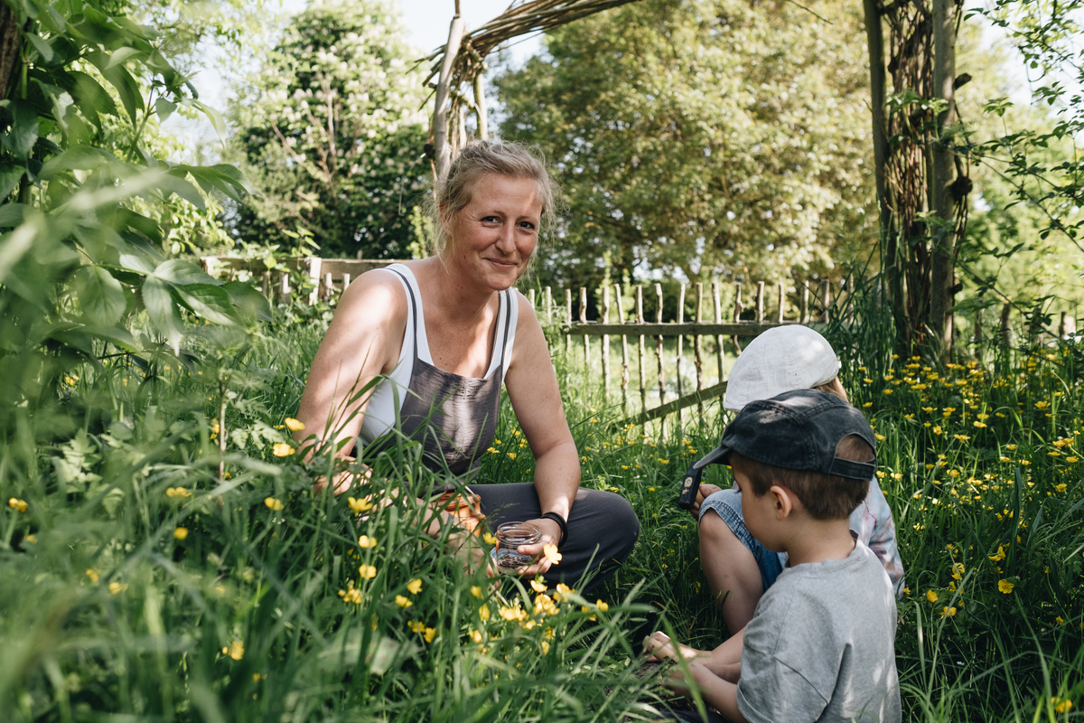 KI generiert: Eine Frau und zwei Kinder sitzen in einem Garten voller Blumen.