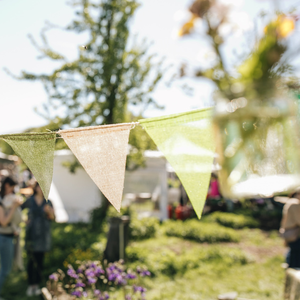 KI generiert: Bunte Wimpelketten hängen über einem sonnigen Gartenfest.