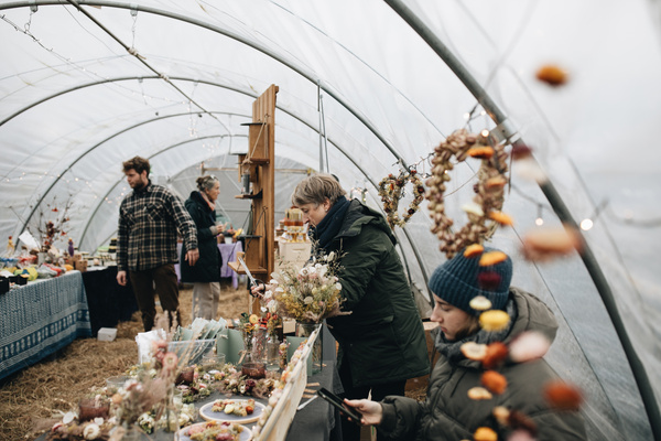 KI-generierte Beschreibung: Menschen auf einem Bio-Bauernmarkt.