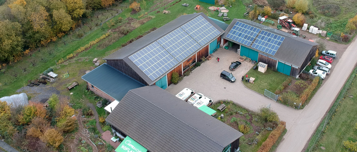 KI generiert: Luftaufnahme eines Bauernhofs mit Solarpaneelen auf den Dächern.