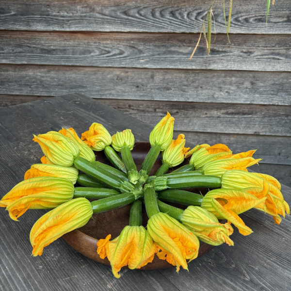 KI generiert: Zucchiniblüten auf einem Holztisch in einer Schale arrangiert.