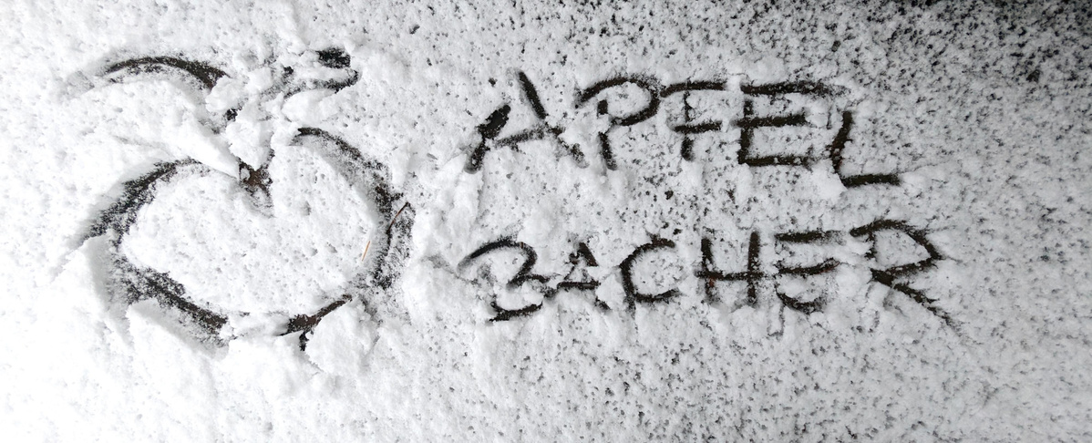 KI generiert: Ein Apfel gezeichnet im Schnee mit dem Text "APFEL BACHER".