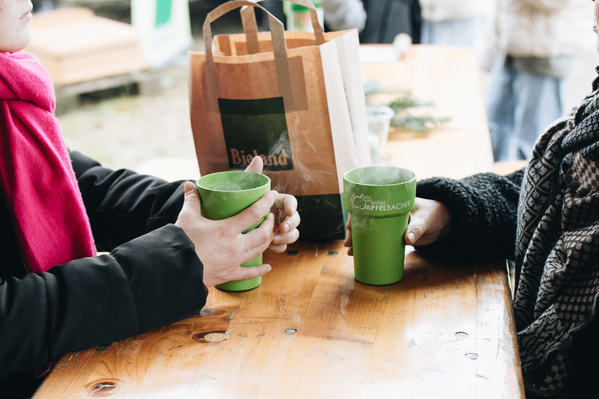 KI-generierte Beschreibung: Menschen trinken Kaffee in Pappbechern auf einer Veranstaltung.