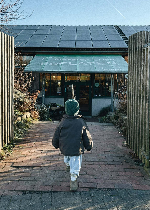 KI generiert: Ein Kind läuft auf einen Hofladen zu. Schildtext: "GÄPPELBACHER HOFLADEN Bioland".