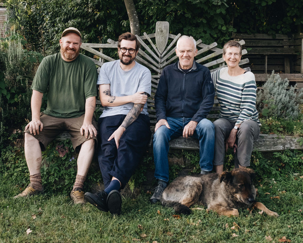 KI generiert: Vier Menschen sitzen auf einer Bank im Garten, neben ihnen liegt ein Hund.